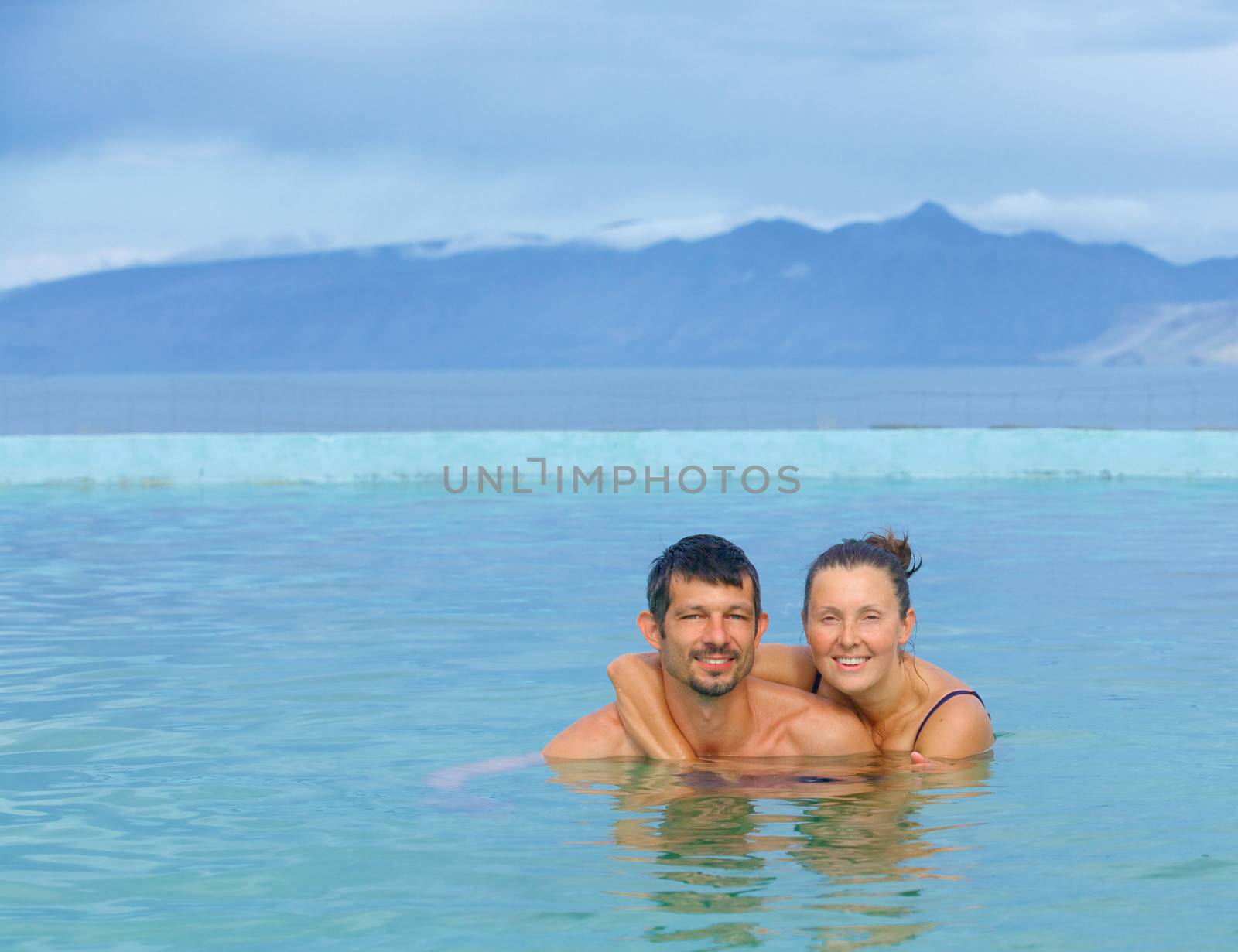 Smiling happy couple in geothermal mineral pool. Iceland