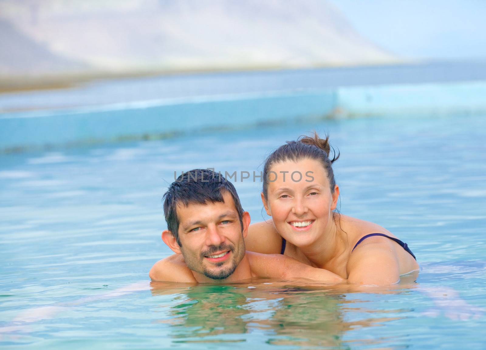 Smiling happy couple in geothermal mineral pool. Iceland