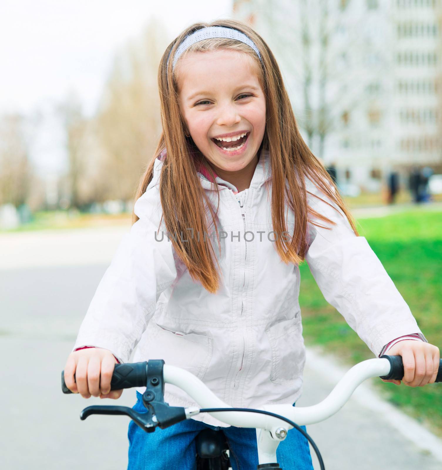 Portrait of a little smiling girl on a bicycle in summer park outdoors