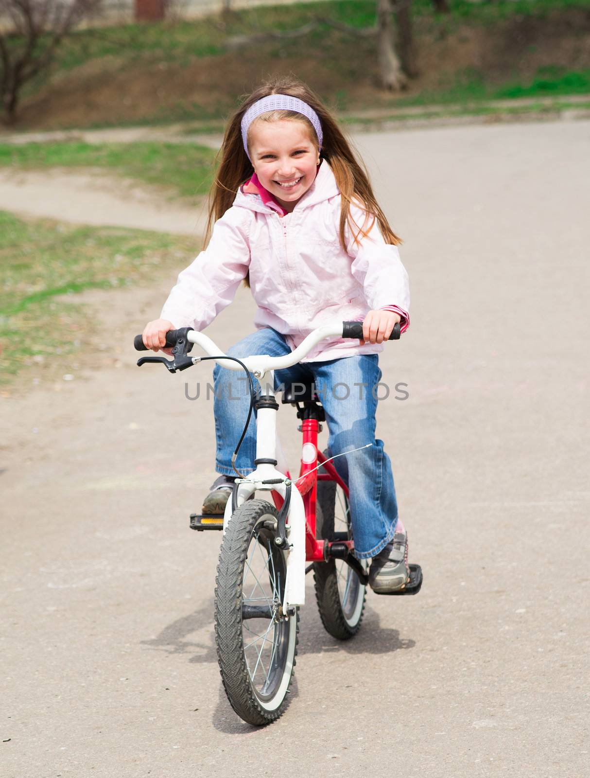 Smiling little girl with bicycle on road