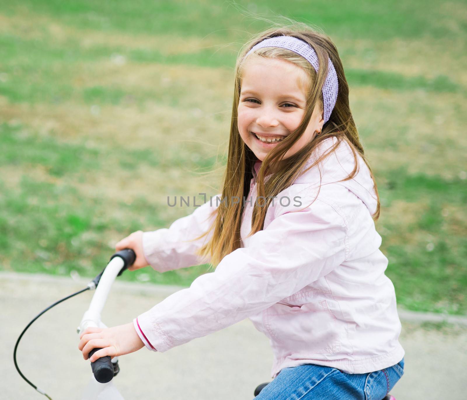 Portrait of cute little girl on a bicycle in summer park