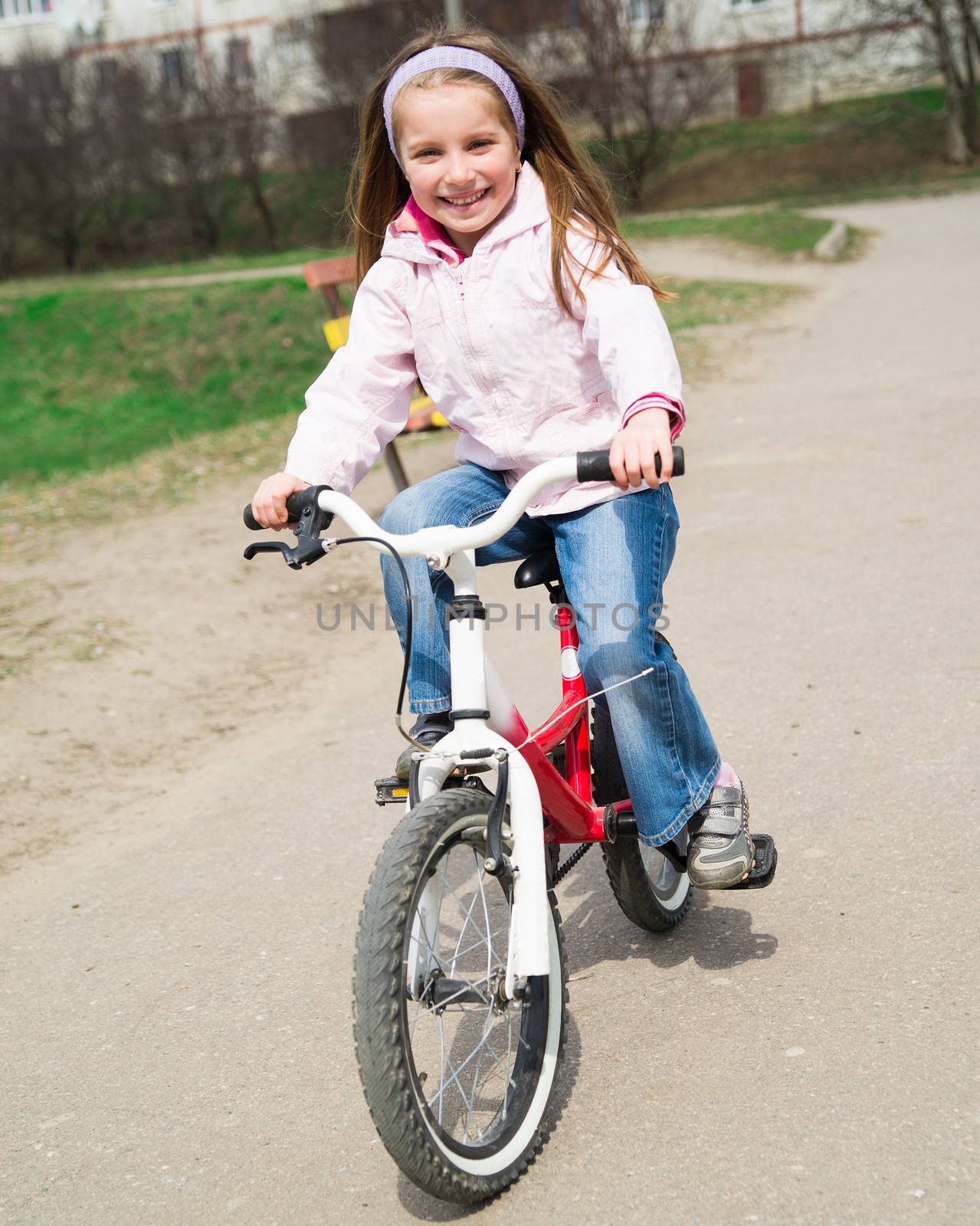 Cute smiling little girl with bicycle on road