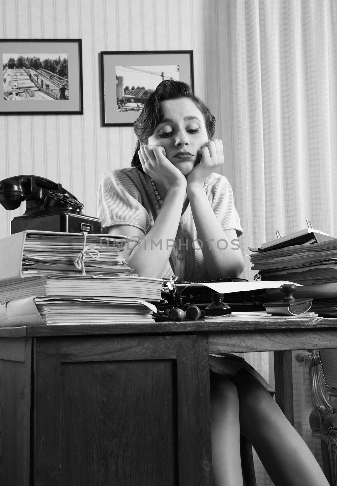 A bored office worker sitting behind a large stack of paperwork