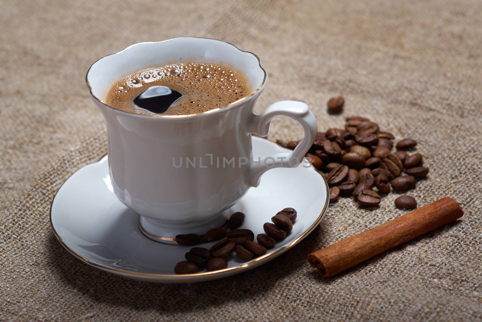 Coffee cup with cinnamon and coffee beans background