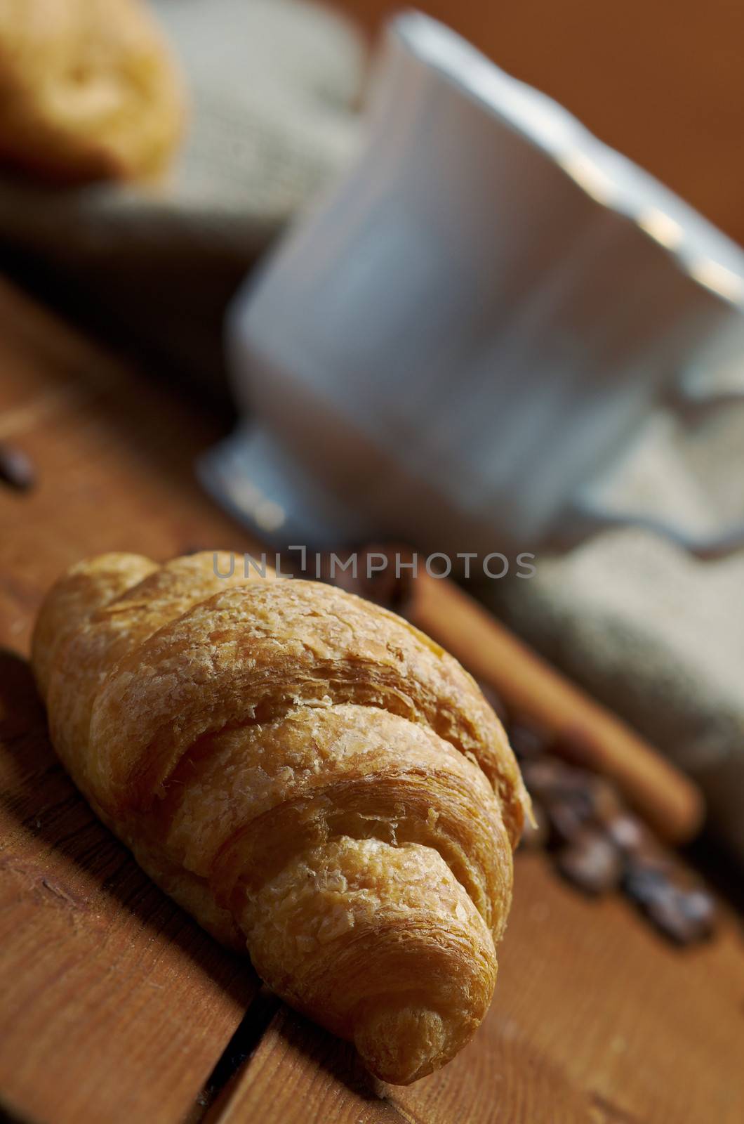 Coffee cup with cinnamon and croissant ,coffee beans background