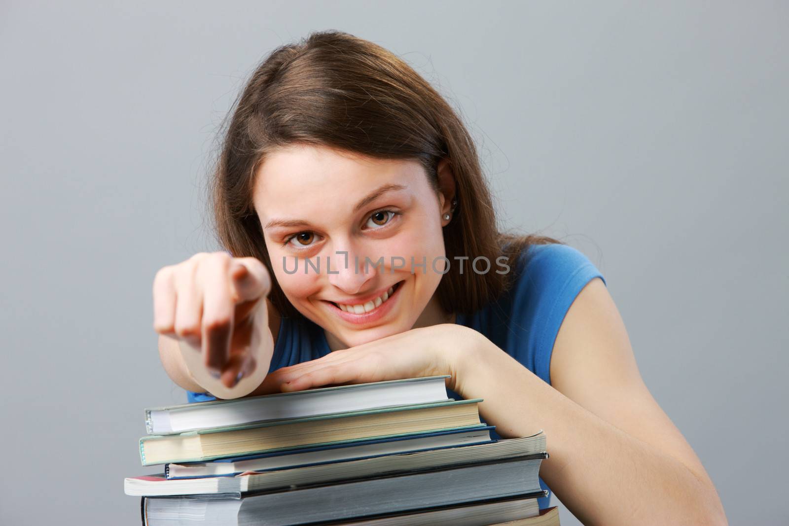 Beautiful girl student with stack of books pointing
