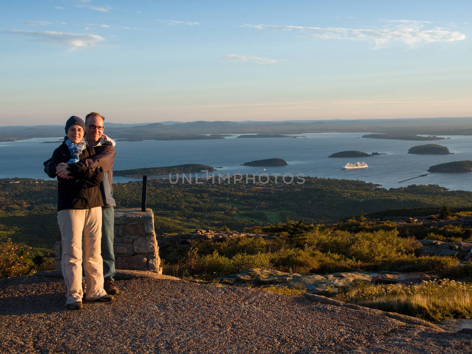 Couple at sunrise over the sea on top of Cadillac Mountain in Acadia National Park