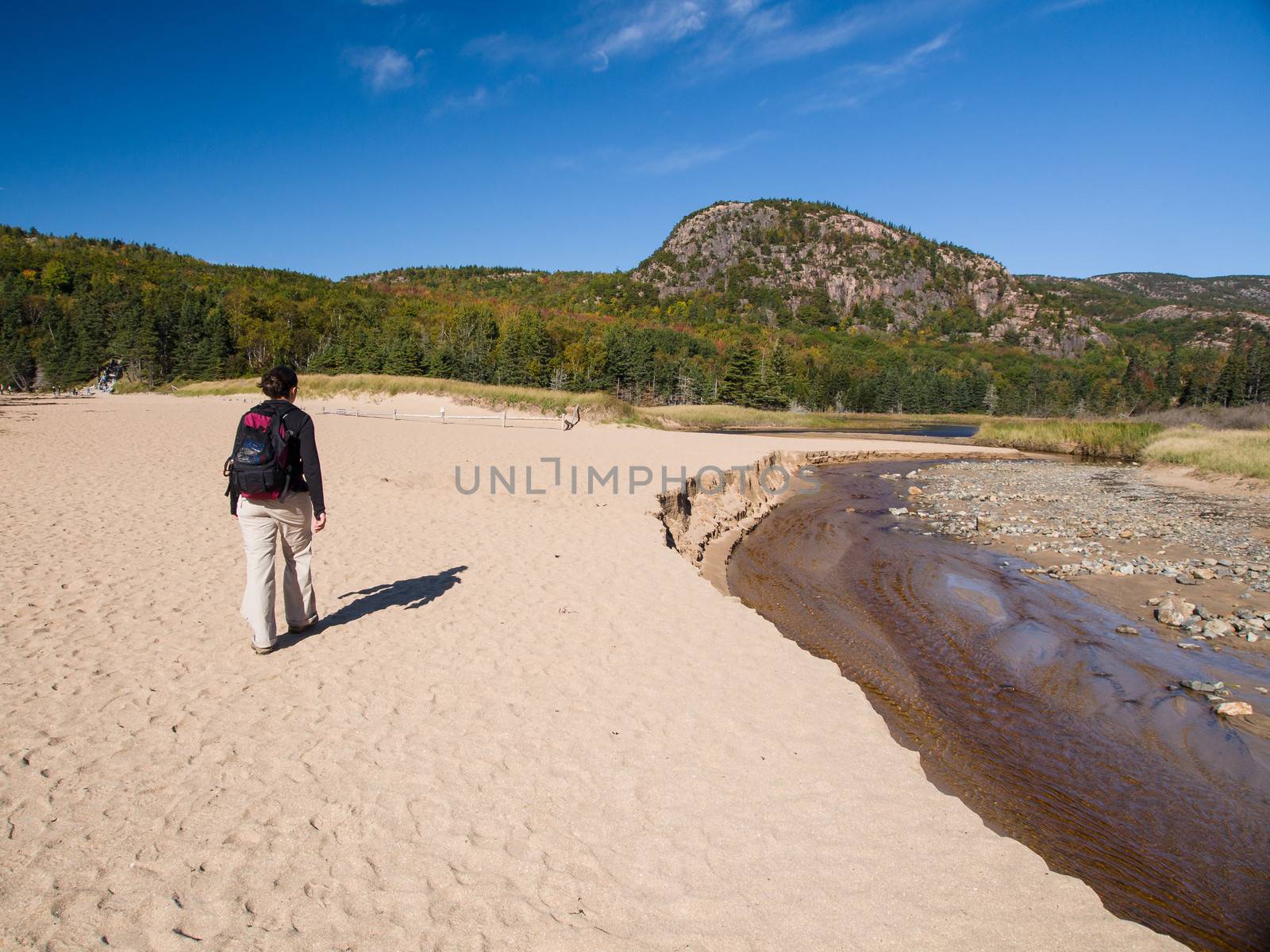 Woman walking on the sand near a river in Acadia National Park