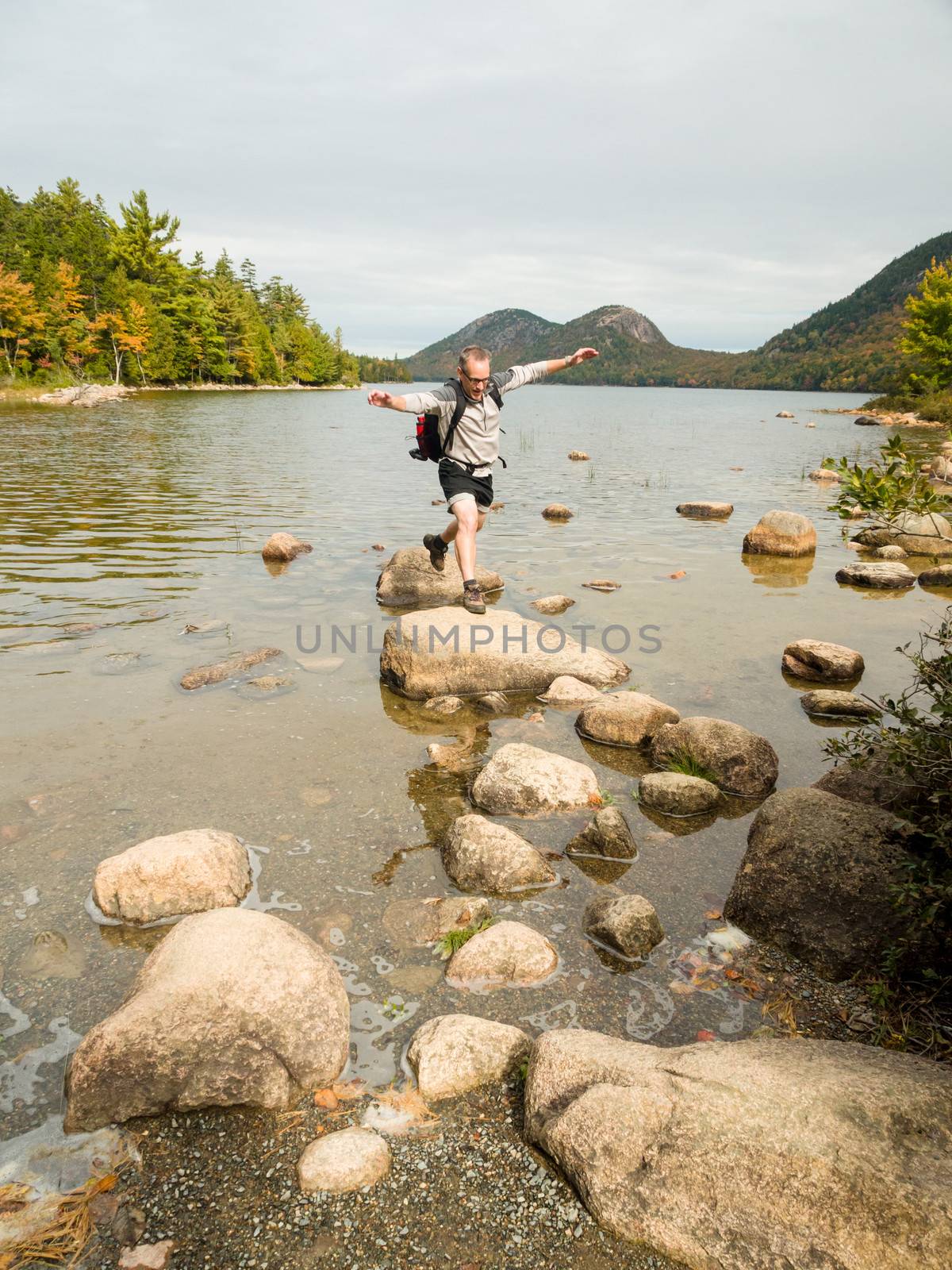 Man jumping on rocks in a lake in Acadia National Park