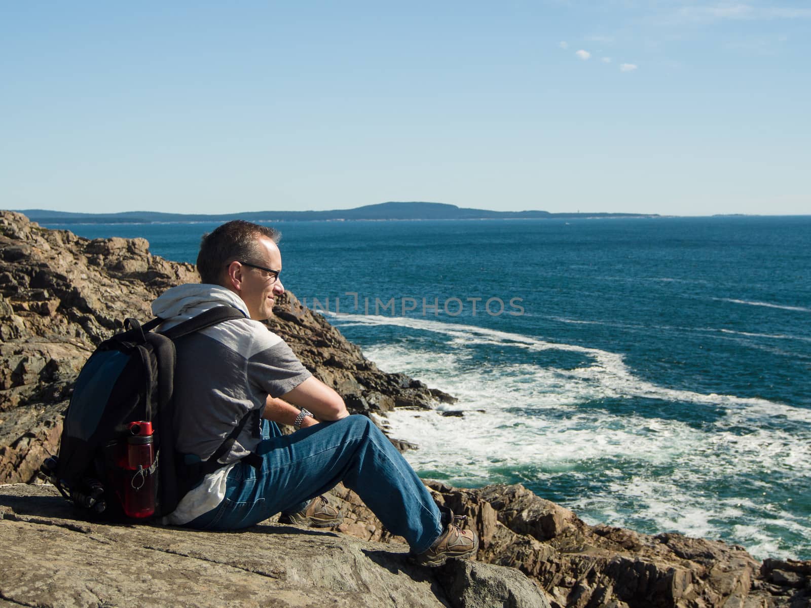 Man resting on a rock cliff by the atlantic ocean