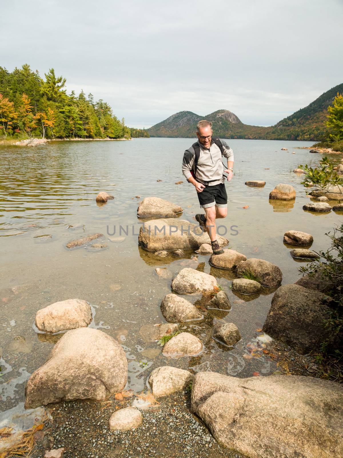 Man jumping on rocks in a lake in Acadia National Park