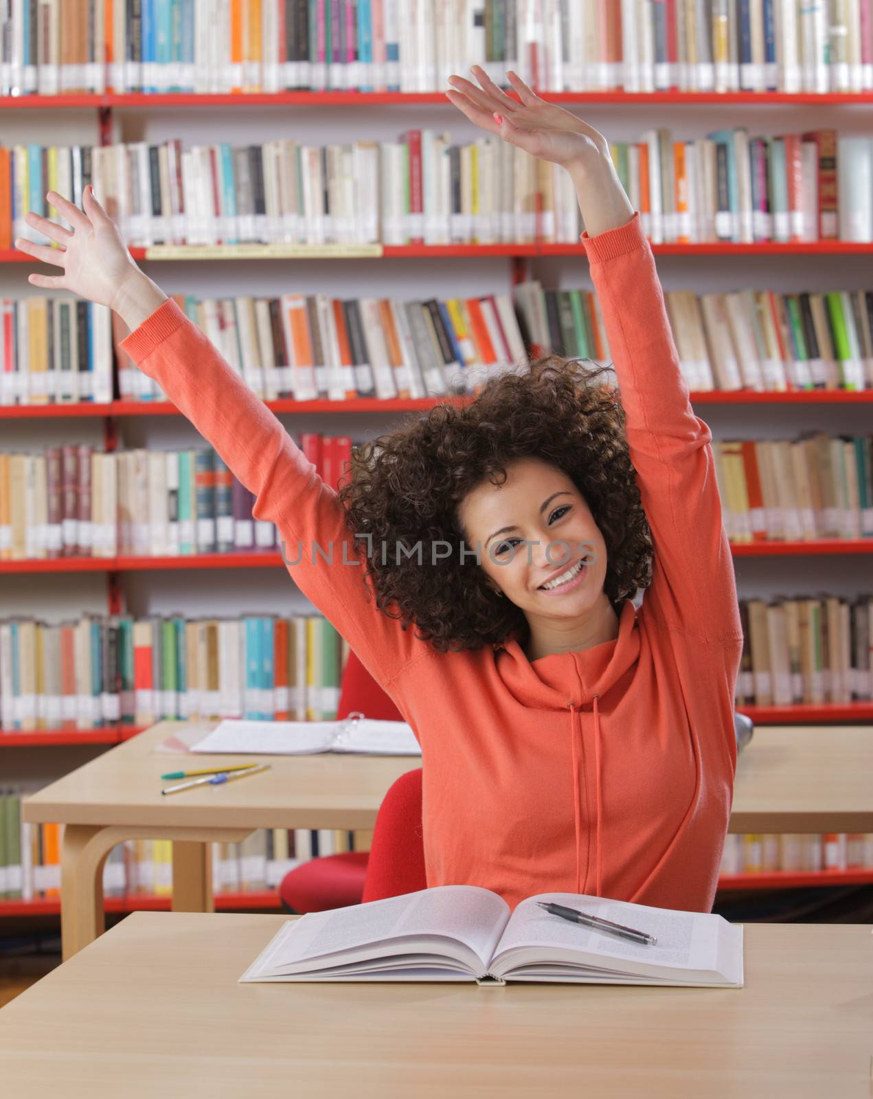 Happy female student with arms raised smiling