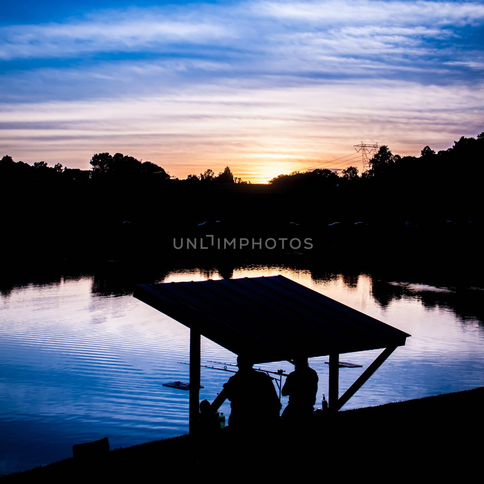 fisherman fishing at sunset on a like