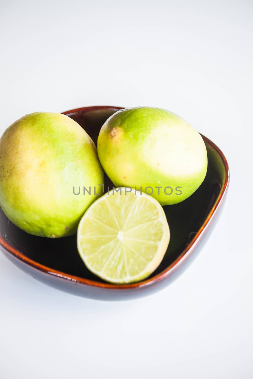 Fresh citrus limes whole and slice in ceramic bowl  by punsayaporn