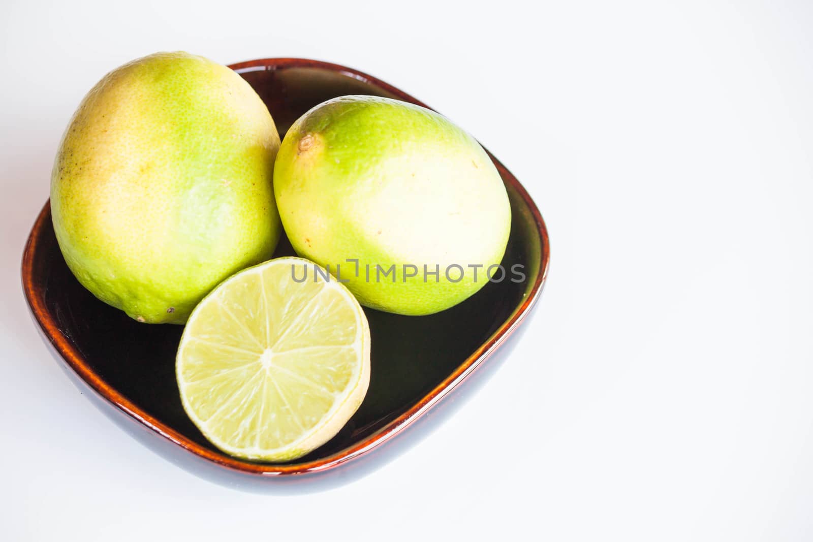 Fresh citrus limes whole and slice in bowl on white background by punsayaporn