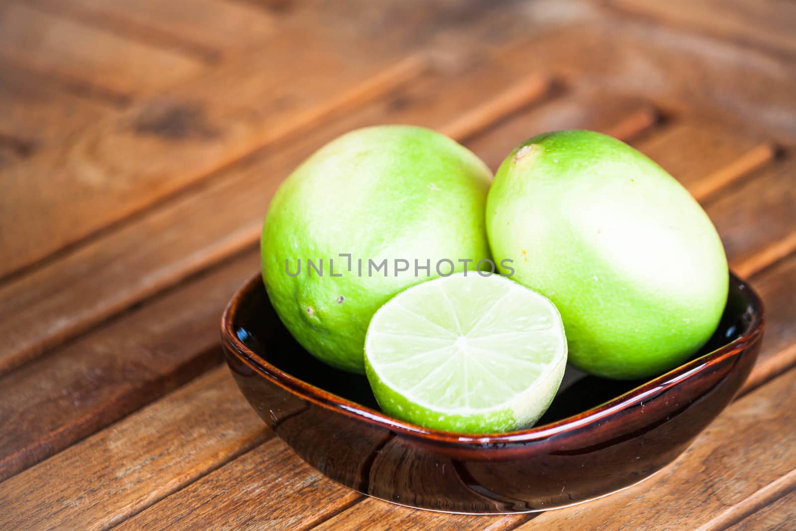 Fresh lime wholes and slice on wood background  by punsayaporn