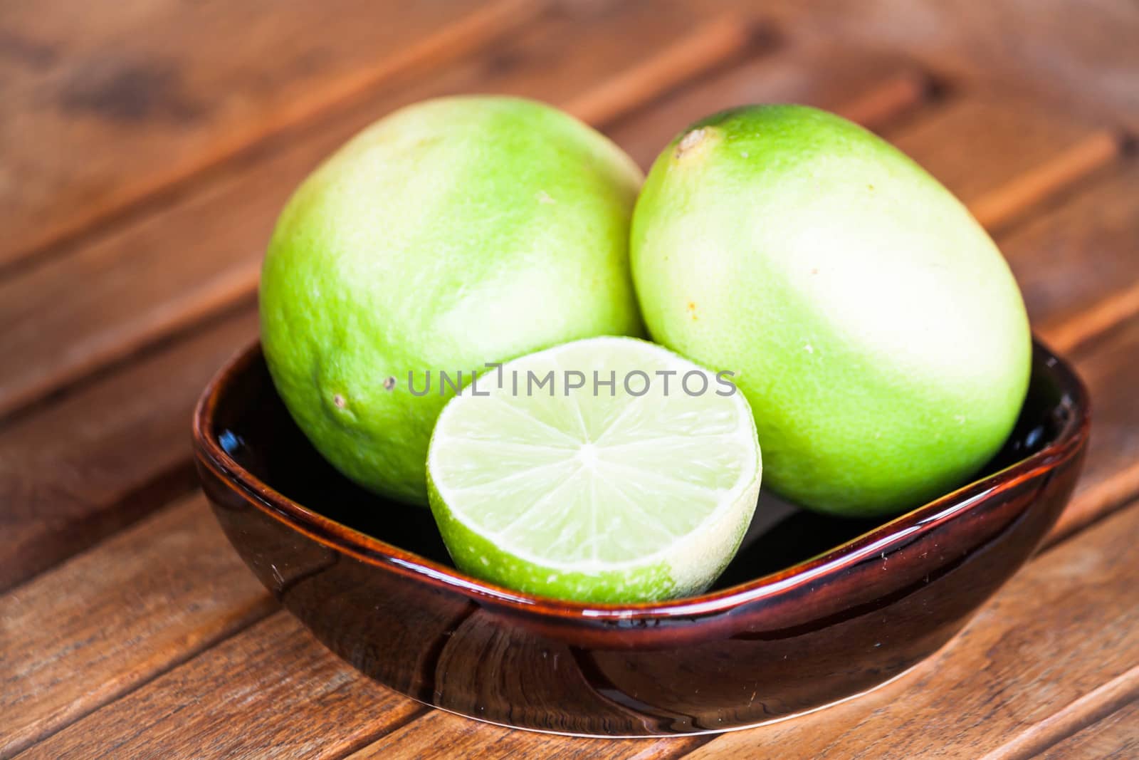 Fresh lime wholes and slice on wood table