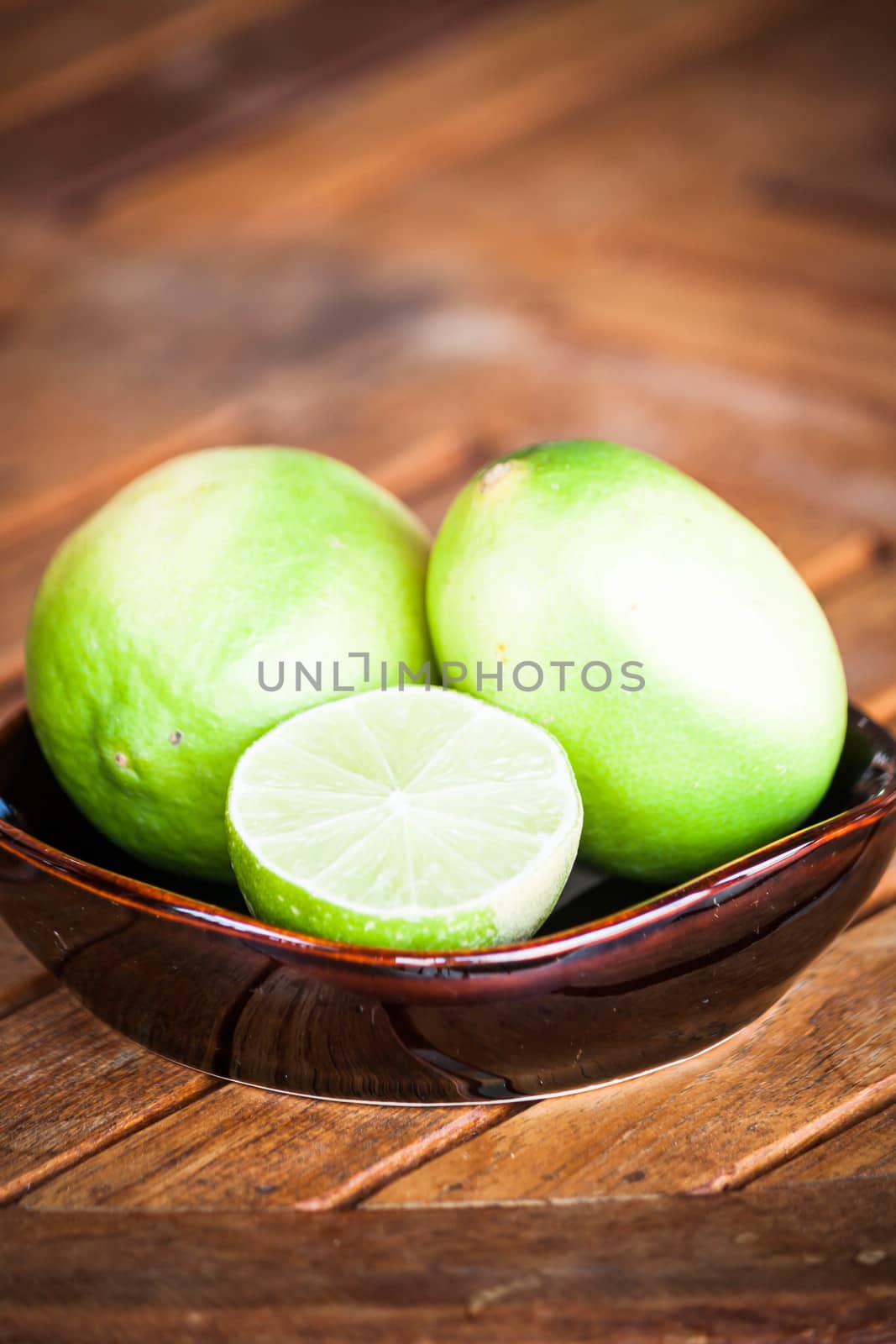 Fresh citrus lime wholes and slice on wood table by punsayaporn