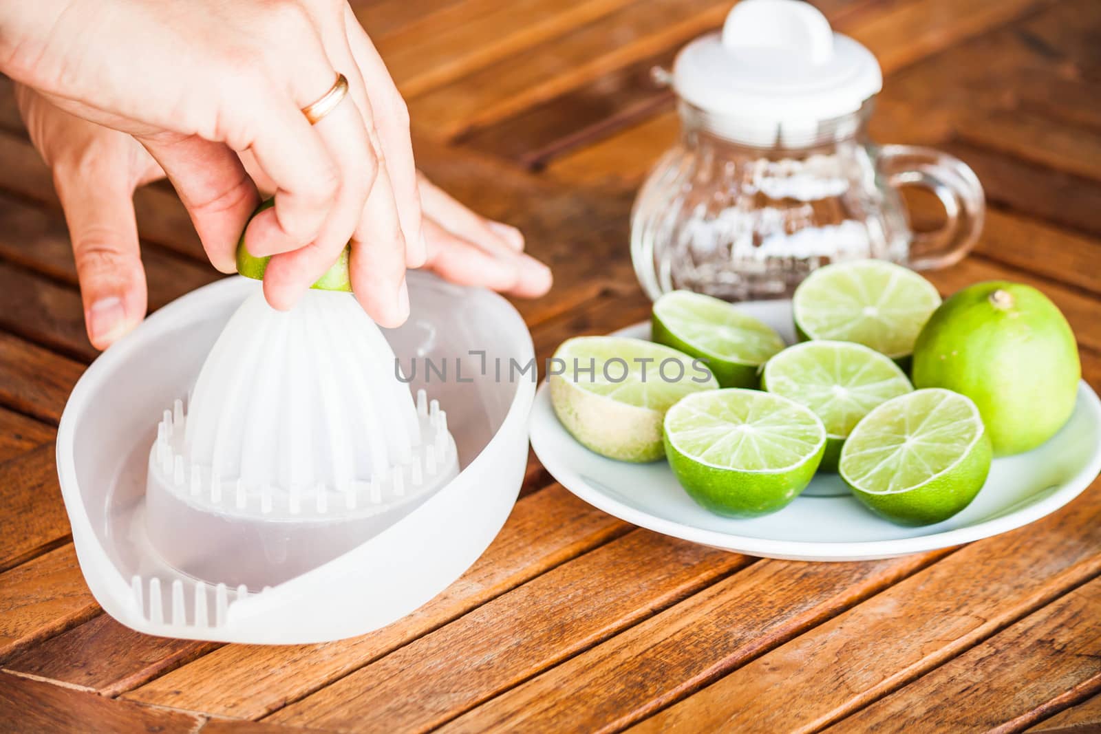 Hand squashing fresh lime on wood counter by punsayaporn