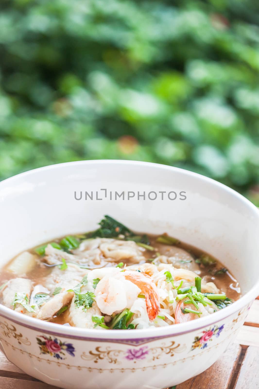 Thai spicy noodles soup with pork and shrimp on wood table