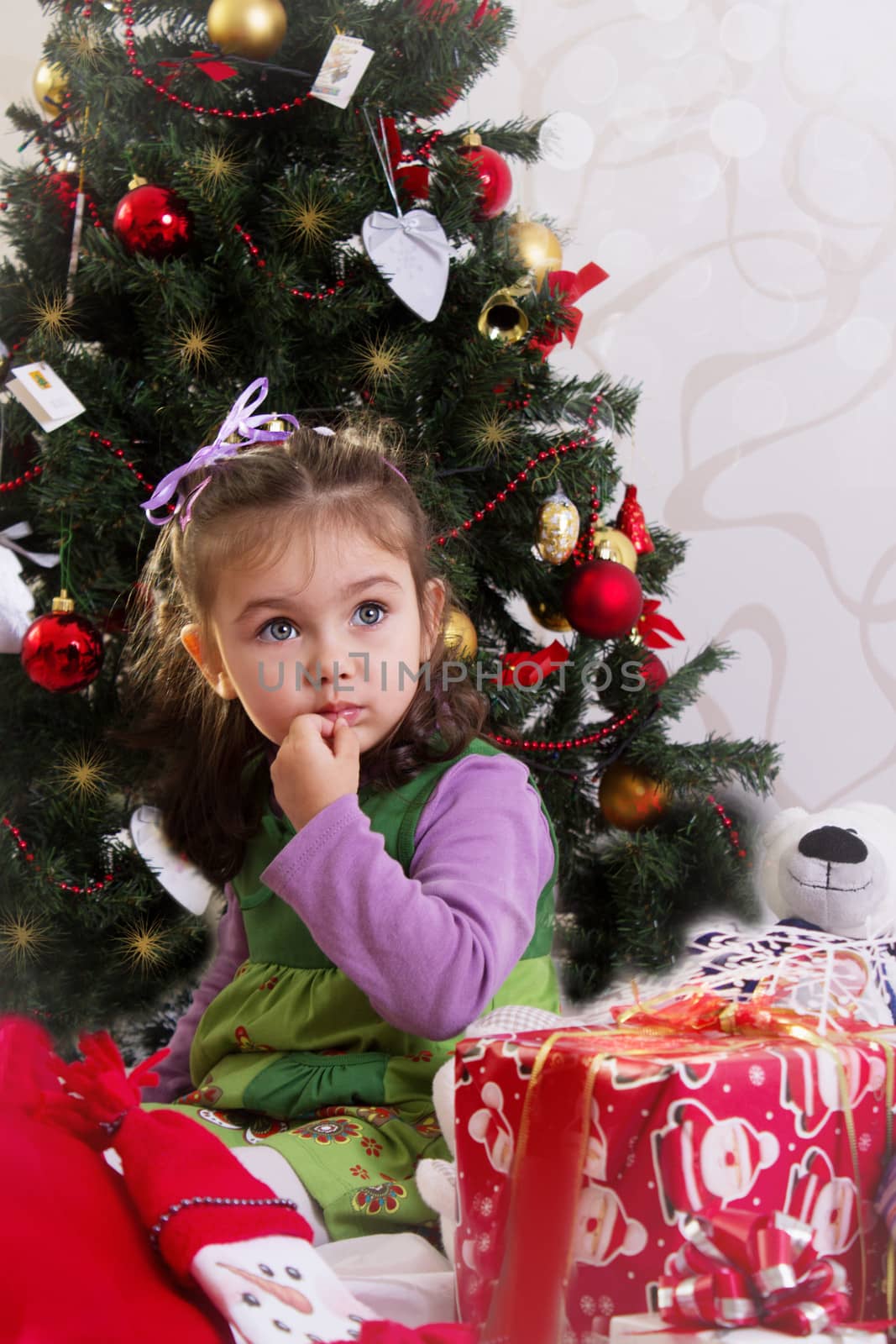 Amazed little girl under Christmas tree with gifts