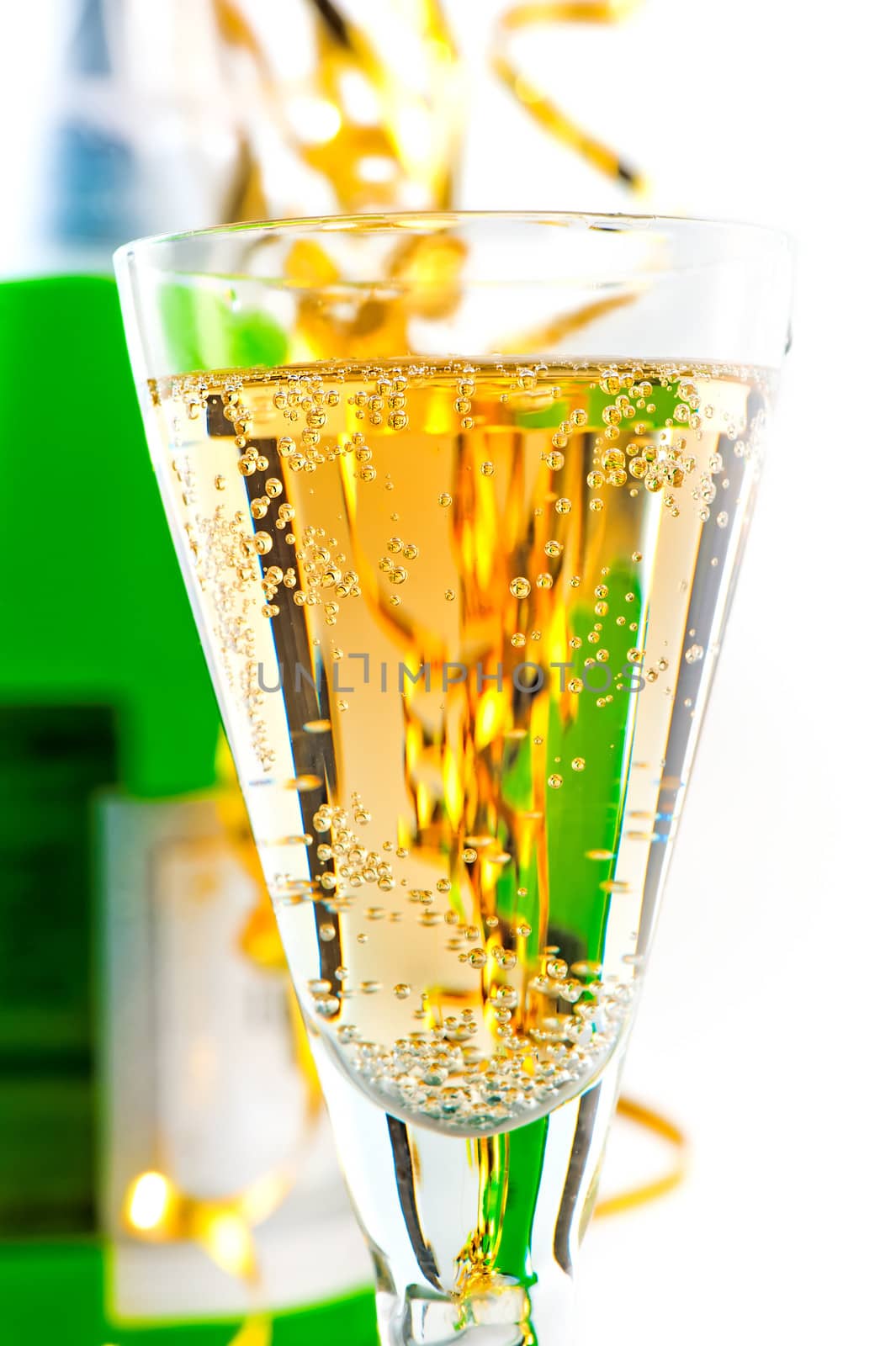 A glass of sparkling wine on the background of the bottle with a festive tinsel.