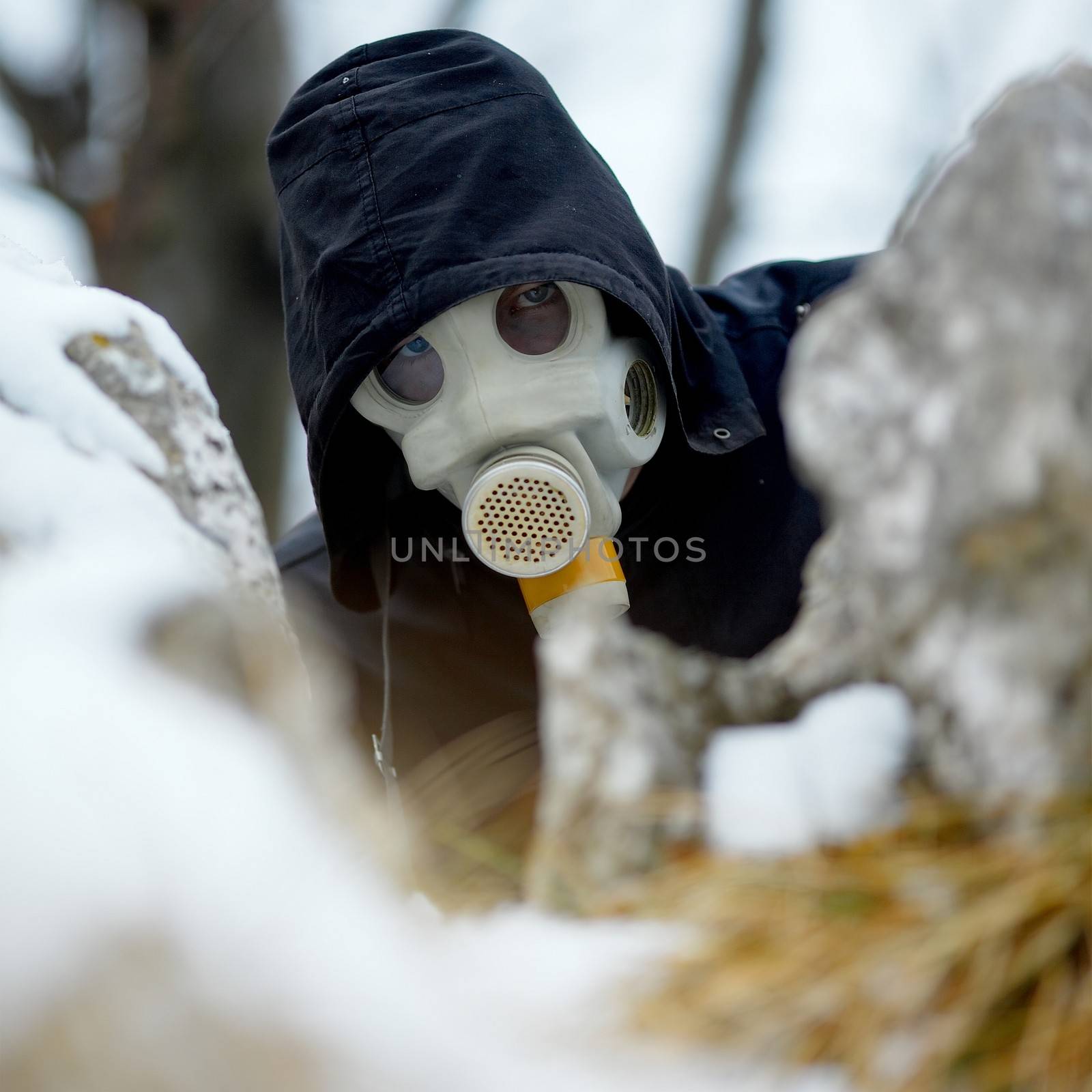 Man in gas mask hiding behind rocks