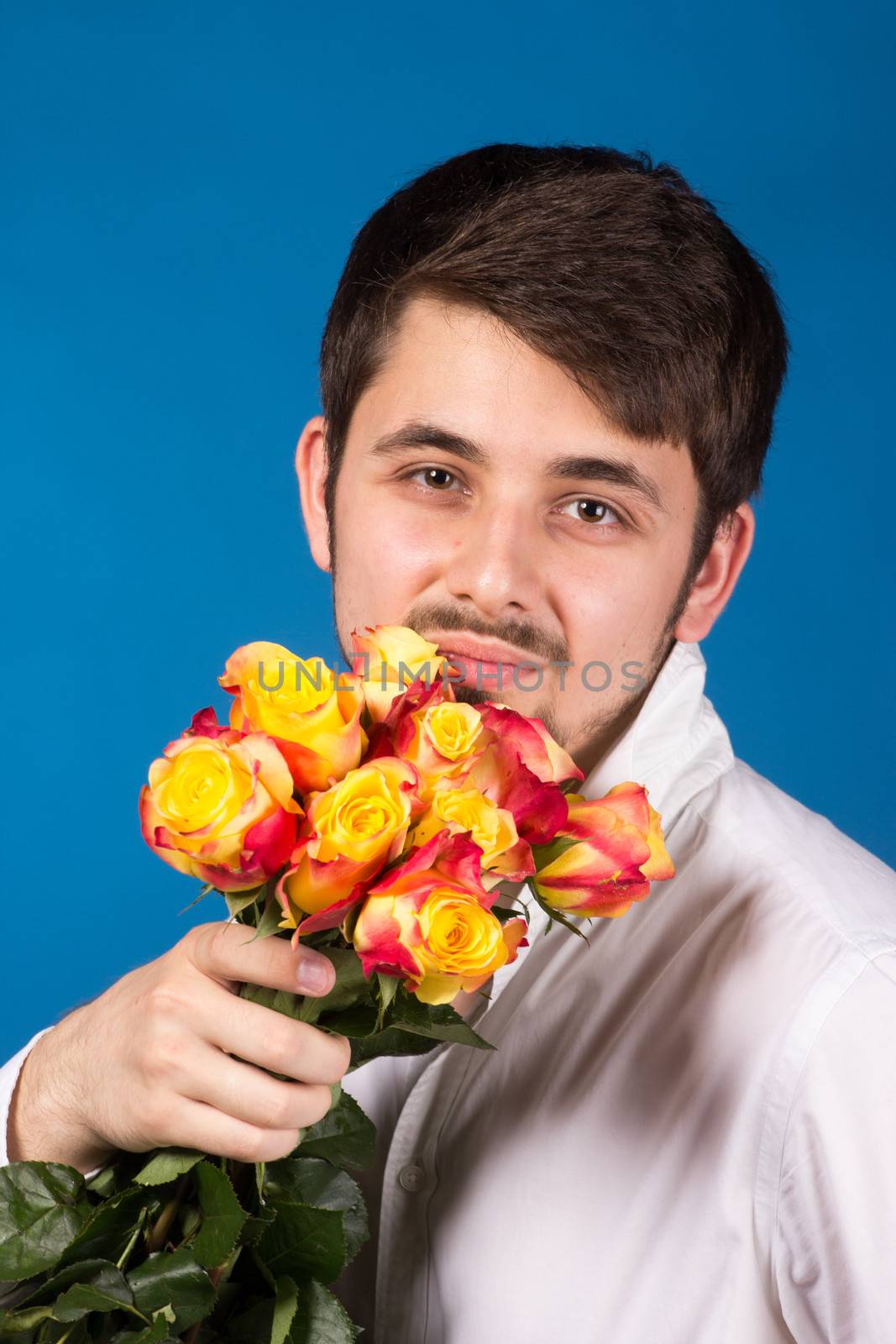 Man with bouquet of red roses. On blue background.