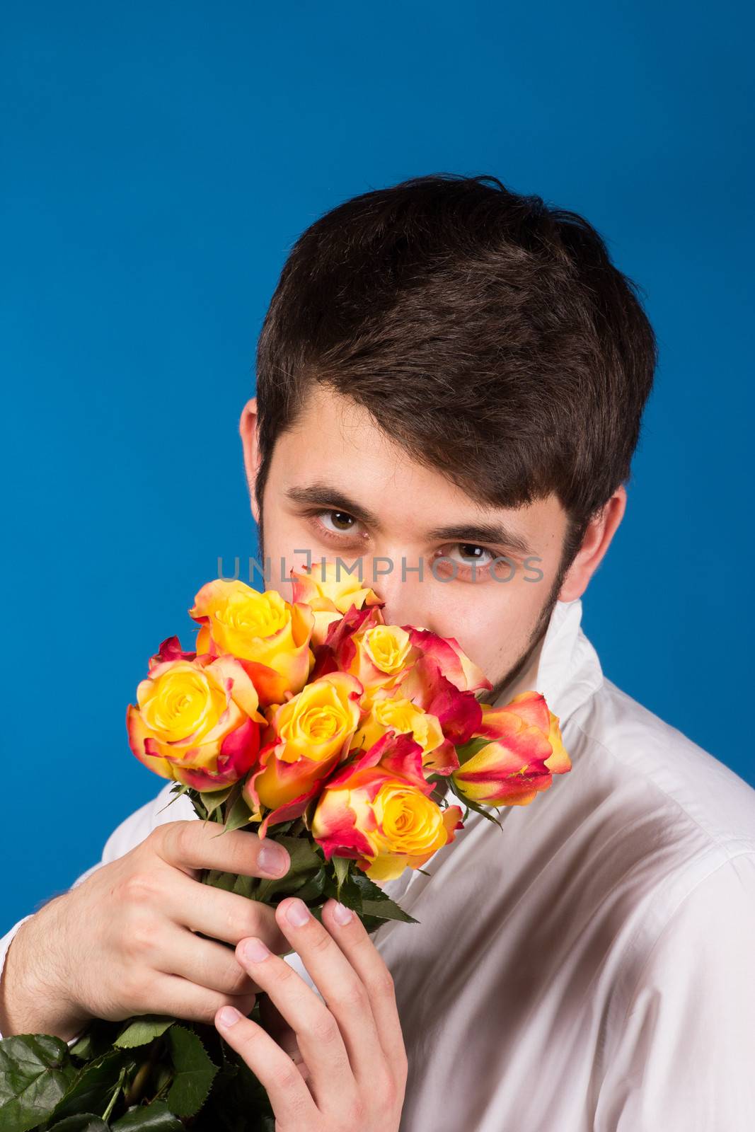 Man with bouquet of red roses. On blue background.