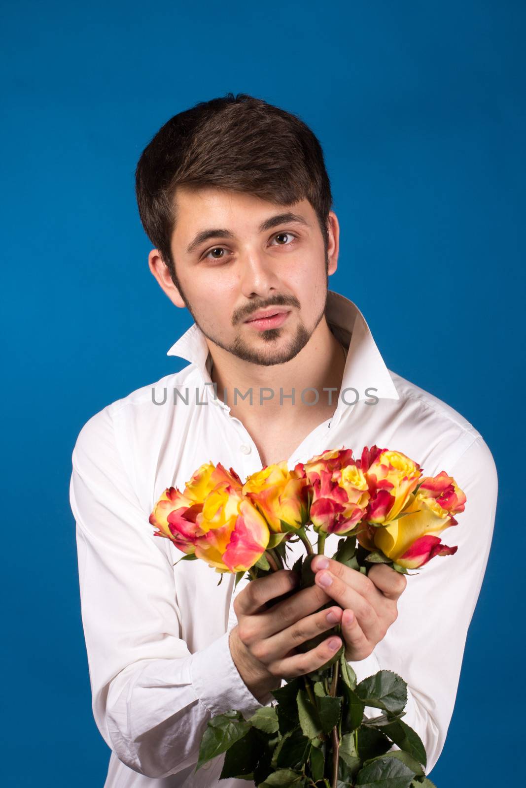 Man with bouquet of red roses. On blue background.