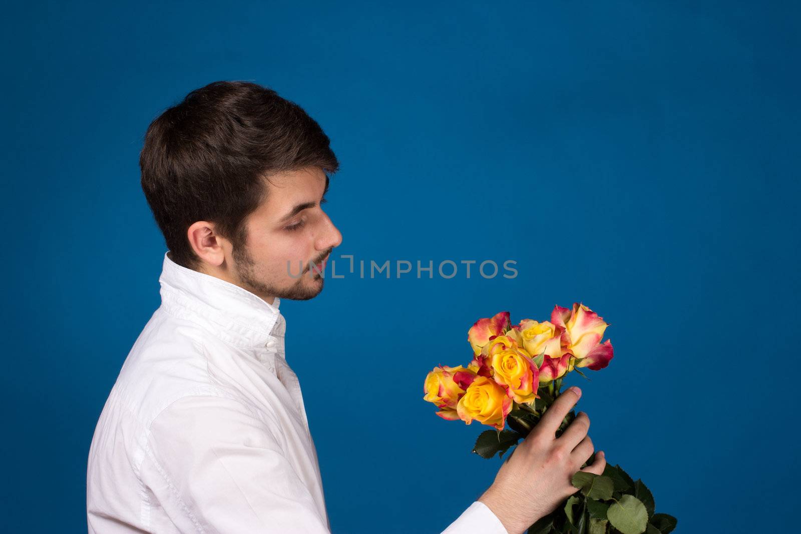 Man with bouquet of red roses. On blue background.