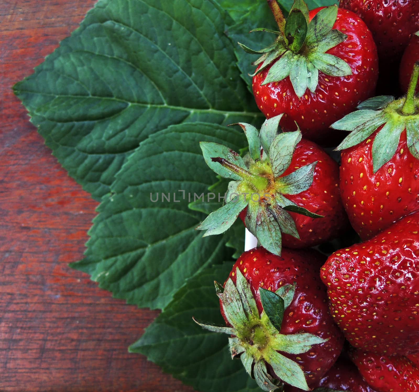 Fresh strawberry with leaf on wooden table by MalyDesigner