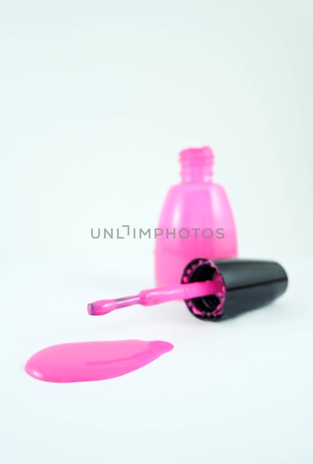 Pink nail polish and brush on white background

