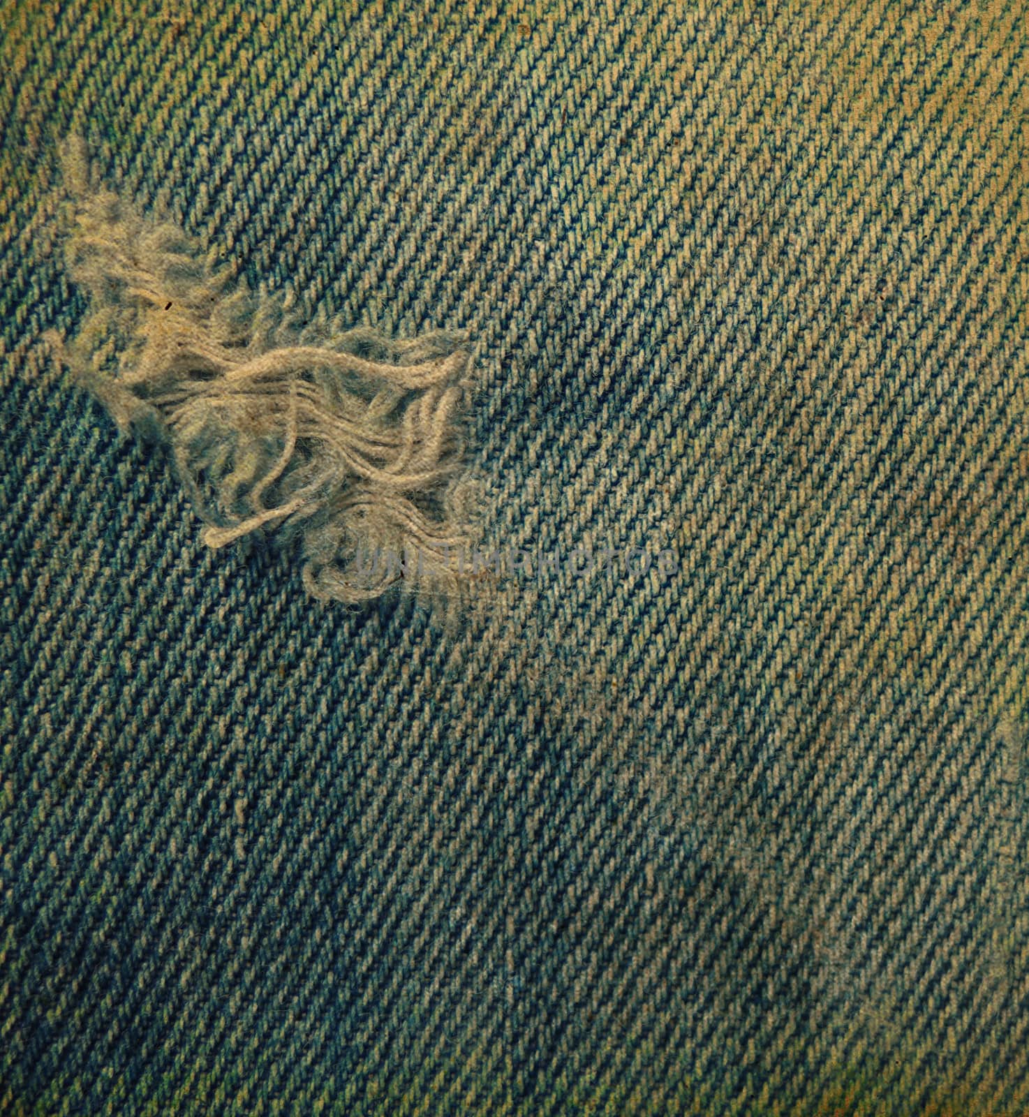 Vintage blue jean texture with a hole and threads showing