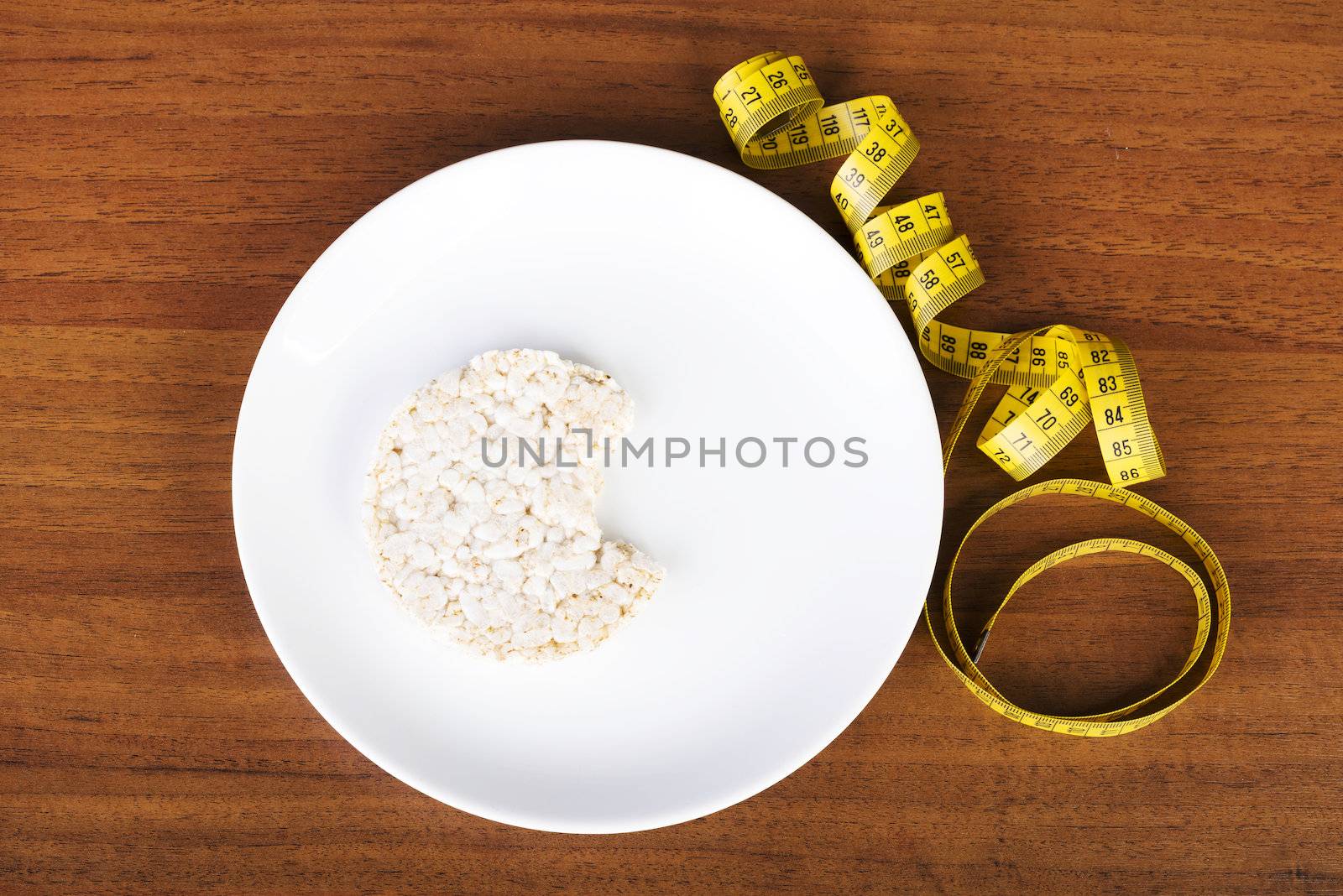 Diet concept. Biten rice cake on plate next to measuring tape.