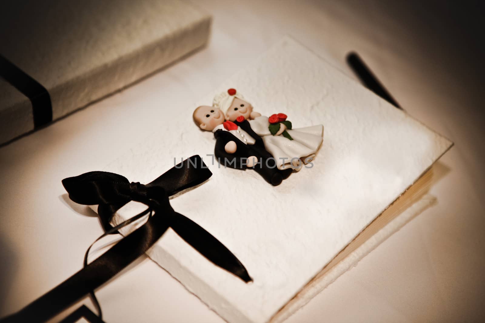 Guest book at a wedding decorated with a bride and groom and decorative bow