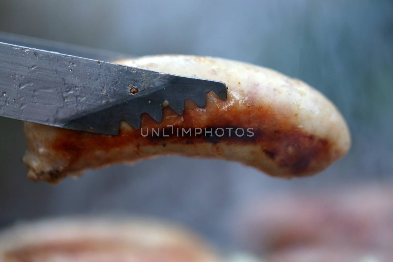 A barbecue tongs with sausege close-up by indigolotos