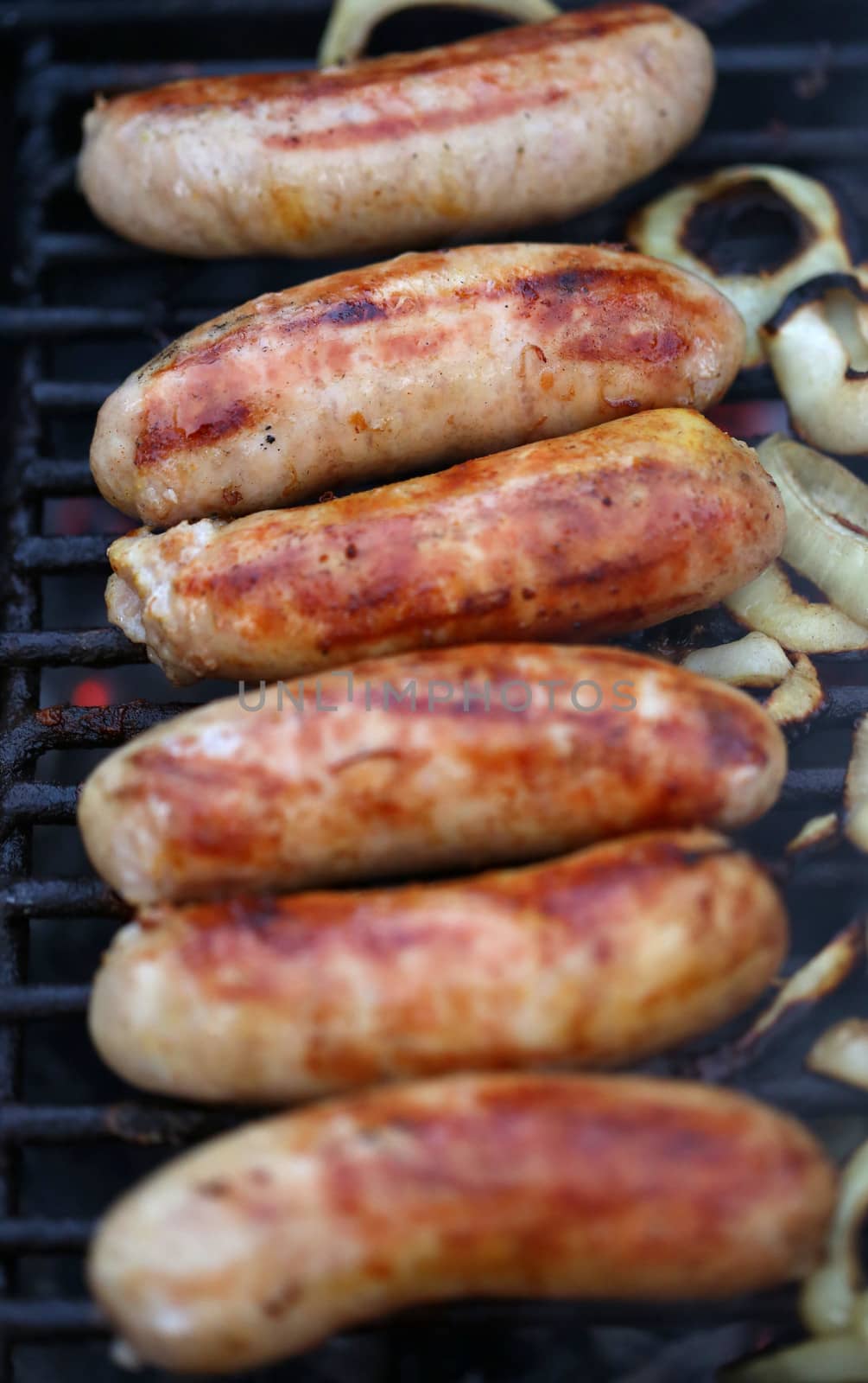 Sausages on grill with onions by indigolotos