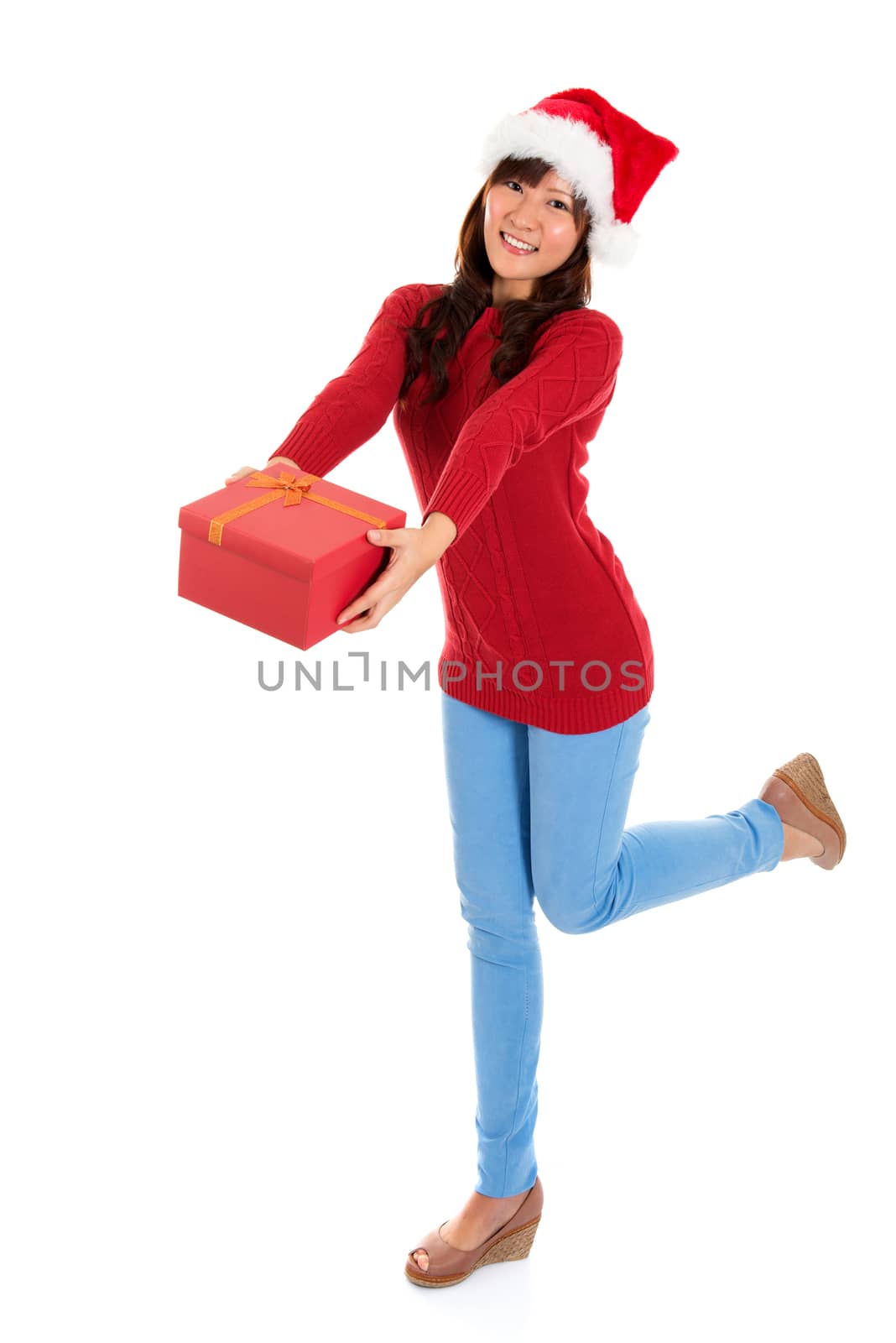 Giving Christmas gift. Young Asian Santa girl deliver a Christmas present. Full body isolated on white background.