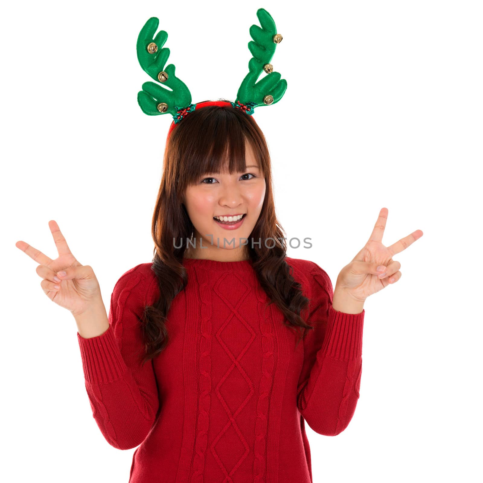 Asian Christmas girl showing victory sign. Lovely young girl gestures v fingers smiling happy isolated on white background.