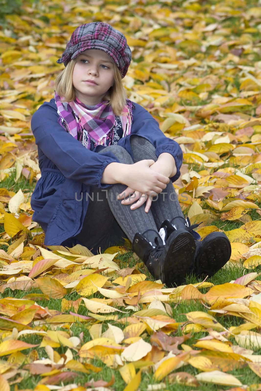 little girl sitting on leaves in the park by miradrozdowski