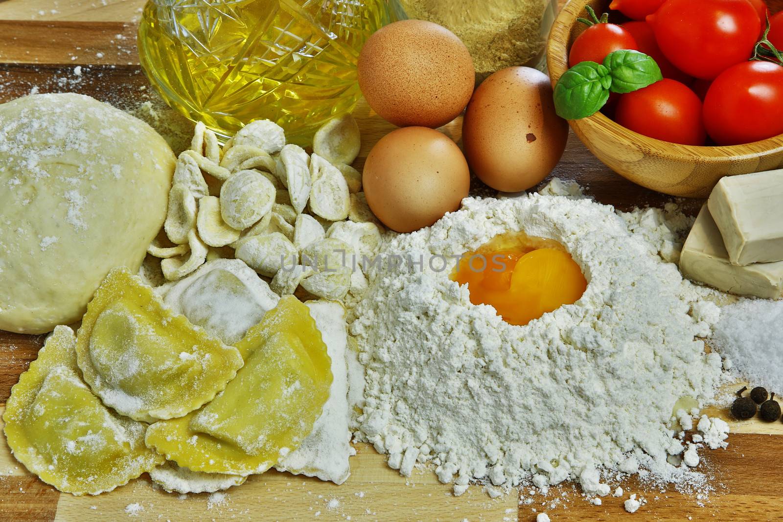 Ingredients for preparation of homemade egg pasta: flour, eggs, examples of egg pasta, tomatoes as a condiment.