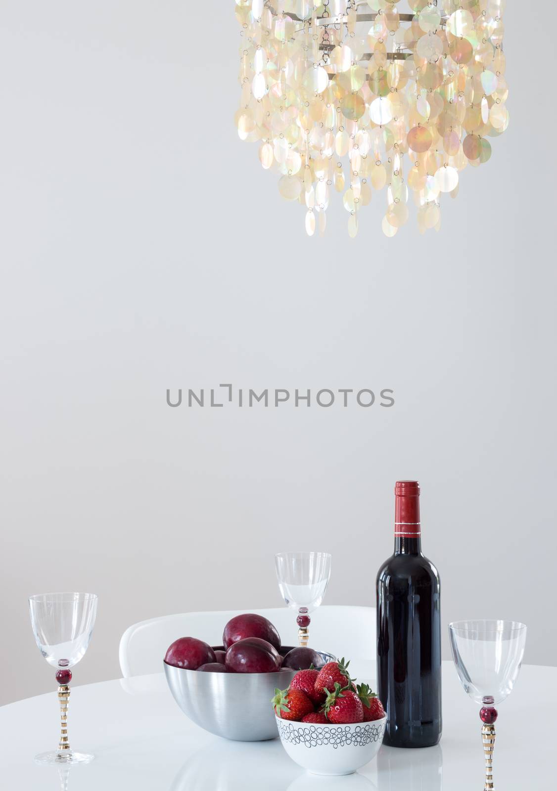 Red wine and fruits on a table, in a room decorated with beautiful chandelier.