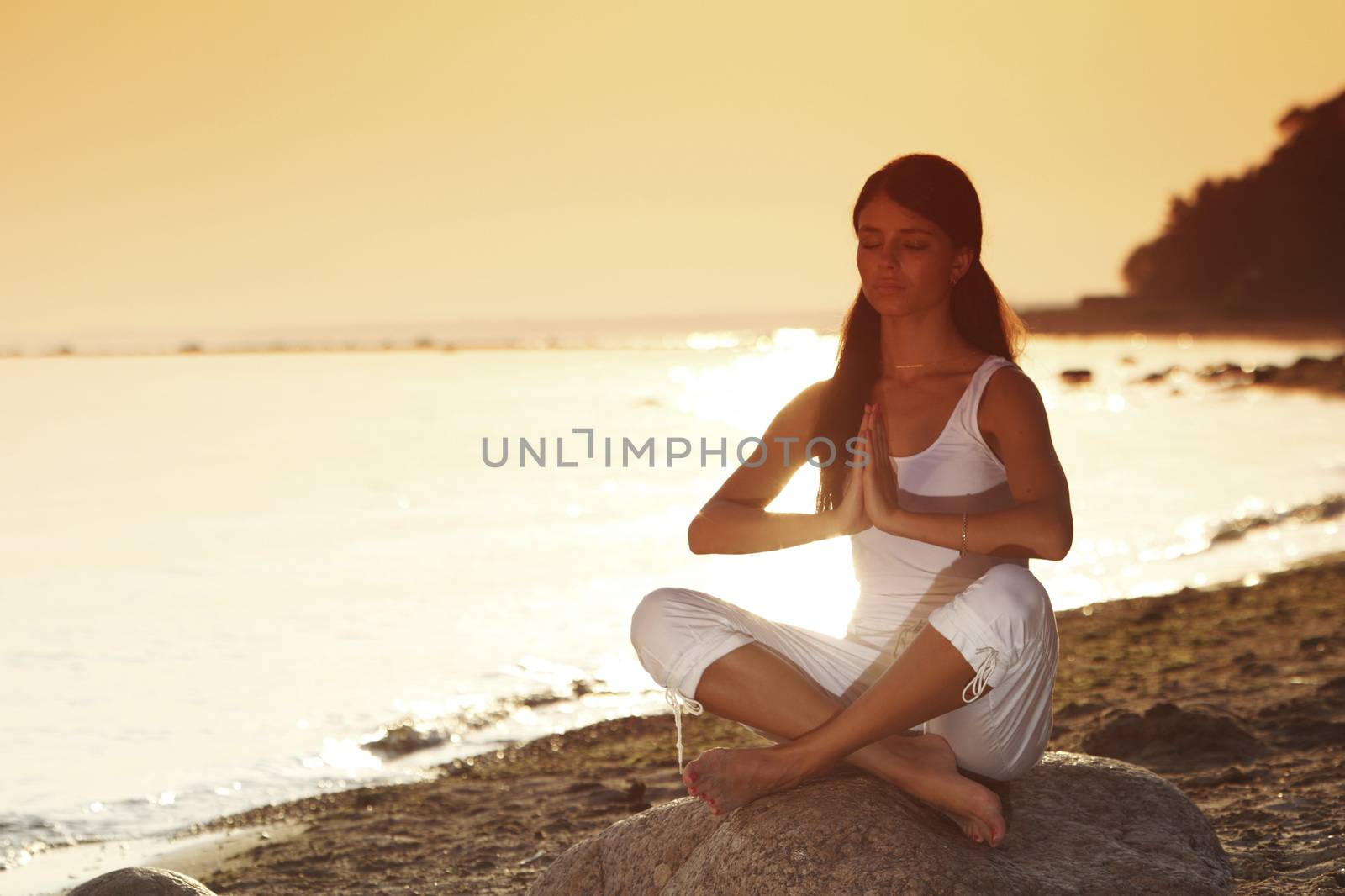 Young woman practicing yoga  near the ocean