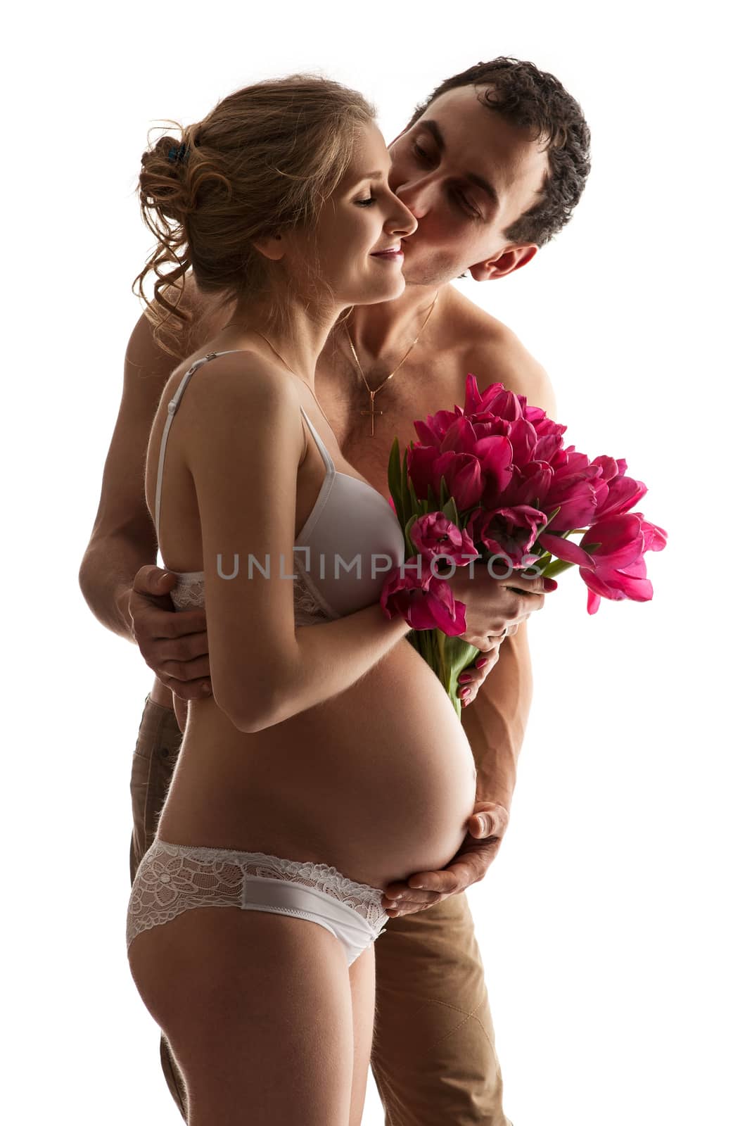 Portrait of young pregnant couple holding flowers over white
