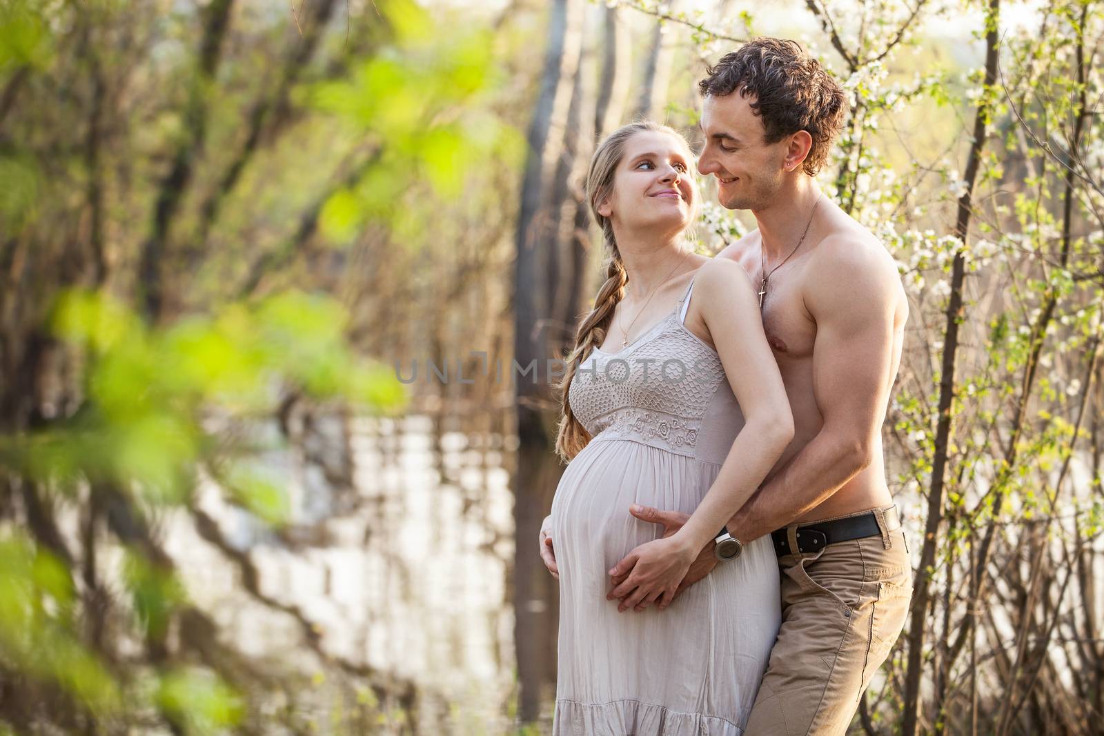 Young pregnant couple at the river in spring