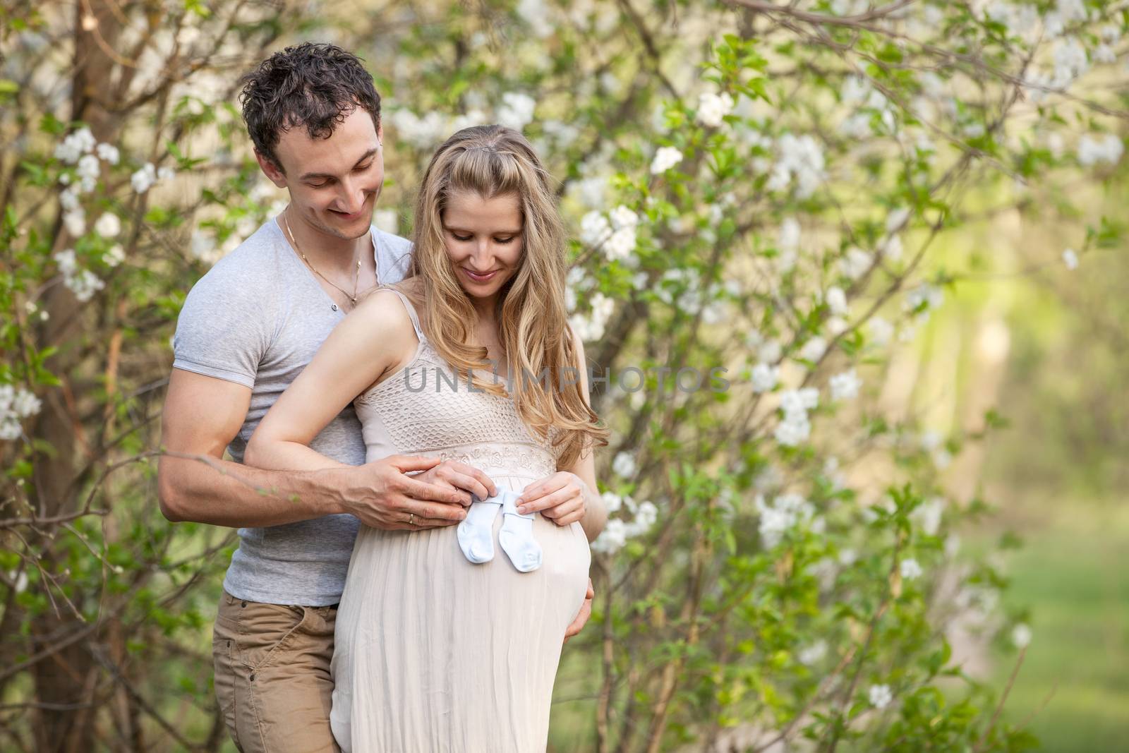 Young pregnant couple outdoors in spring blossom