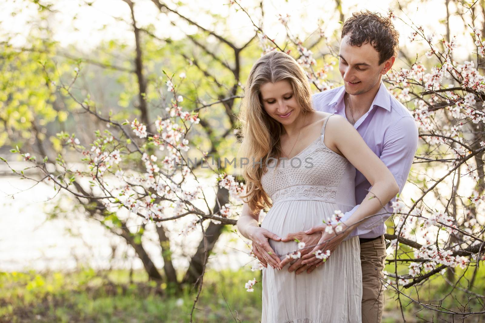 Young pregnant couple outdoors in spring by photobac