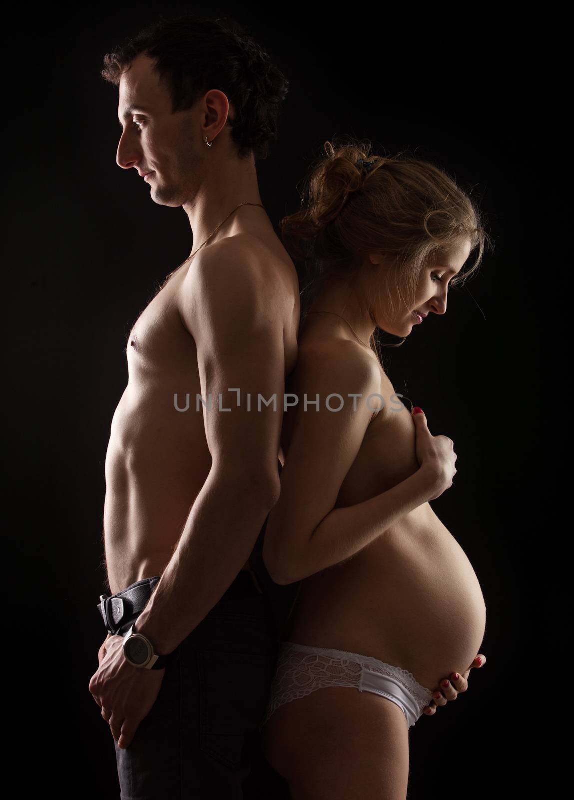 Portrait of young pregnant couple standing back to back
