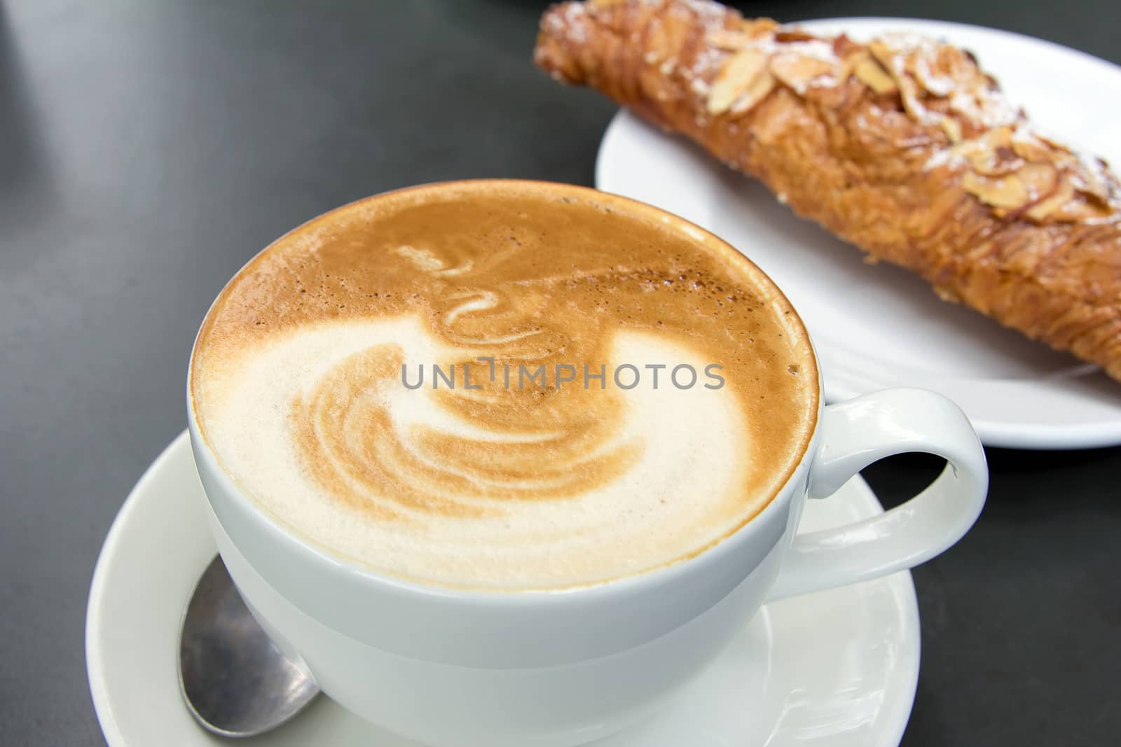 Cup of Caffe Latte with Almond Croissant in Background
